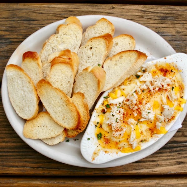 Stan & Joe's Saloon's crab dip, topped with cheese and spices, served with toasted baguette slices.