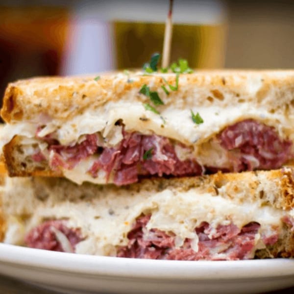 Close-up of a hearty Reuben sandwich with corned beef, sauerkraut, and melted cheese on rye.