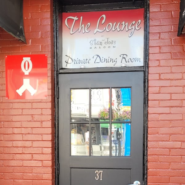 Stan & Joe's Saloon's "The Lounge Private Dining Room" door on a red brick wall.