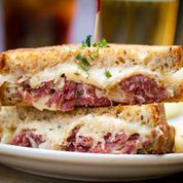 Close-up of a Stan & Joe's Saloon Reuben sandwich, cut in half, revealing corned beef and melted cheese.