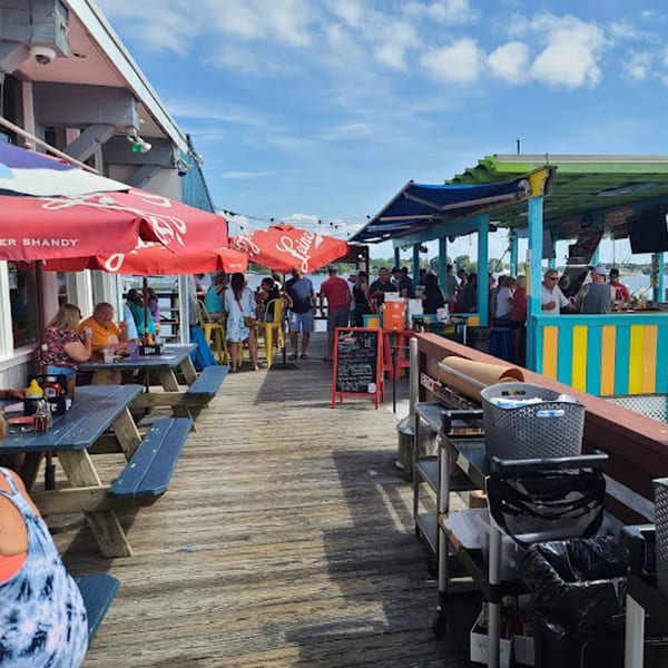 Patrons enjoying food and drinks on a sunny outdoor deck at Stan & Joe's Saloon.