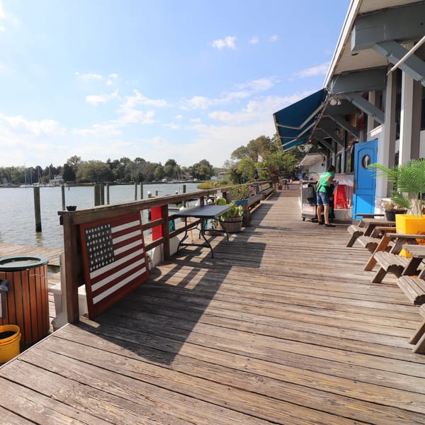 Stan & Joe's Saloon's outdoor wooden deck with a view of the water, boats, and trees.