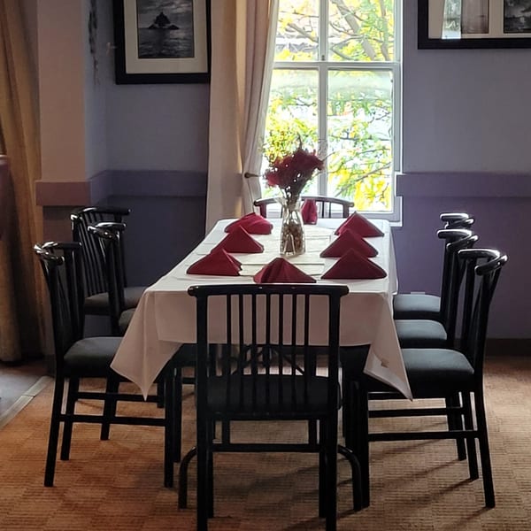 A dining table set with red napkins and a floral centerpiece, ready for guests at Stan & Joe's Saloon.