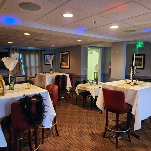 Stan & Joe's Saloon's dining area with tables set for a party, featuring white tablecloths and feather centerpieces.