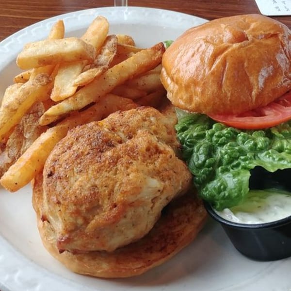 Stan & Joe's Saloon's crab cake sandwich with lettuce, tomato, fries, and tartar sauce.